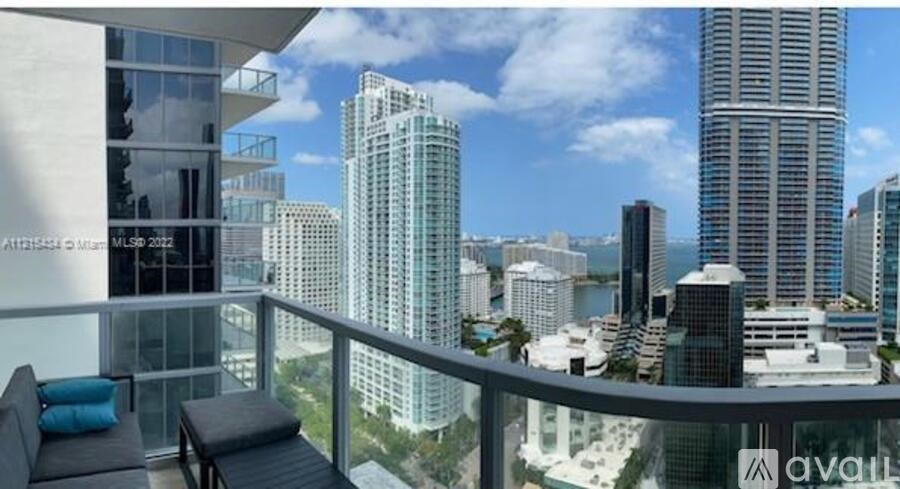 A balcony with a couch and a table overlooking a cityscape.