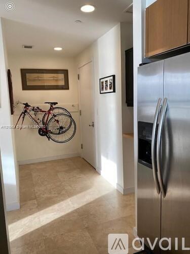 A kitchen with a stainless steel refrigerator and a bicycle hanging on the wall.