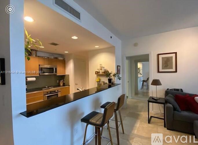 A modern kitchen with a bar stool and a dining table.