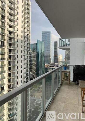 A balcony with a glass railing overlooks a cityscape.