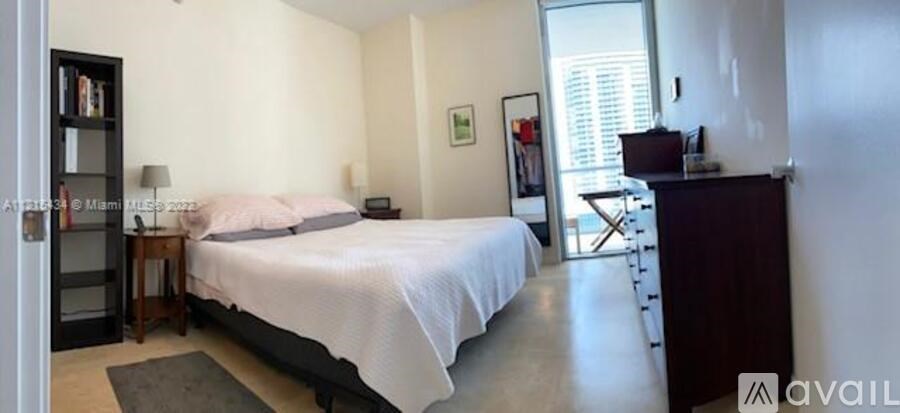 A bedroom with a large bed and a desk with a chair.