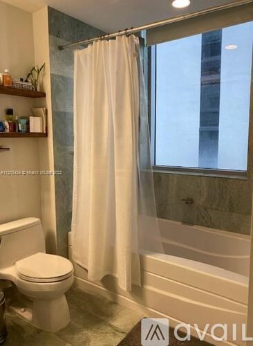 A white toilet sits next to a bathtub in a bathroom.