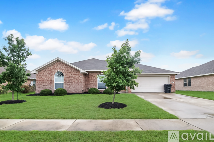 A house with a driveway and two trees in front.