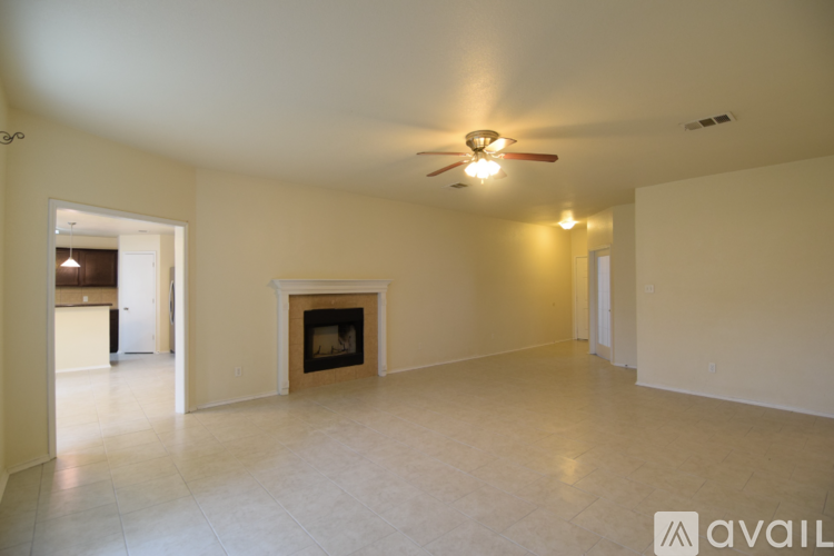 A spacious living room with a fireplace and a ceiling fan.