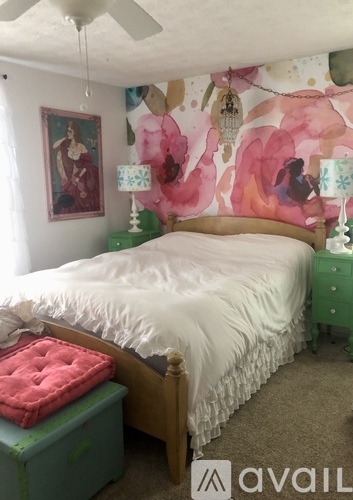 A bedroom with a bed, green nightstand, and a painting on the wall.
