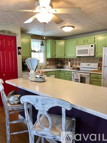 A kitchen with green cabinets and a white counter.
