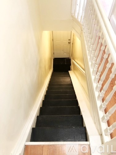 A staircase with a wooden handrail and black steps.