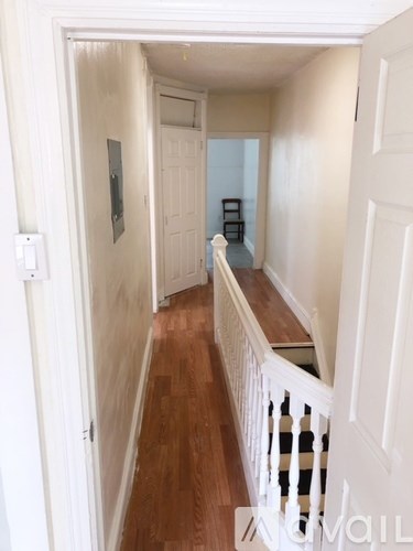 A hallway with a white railing and wooden floors.