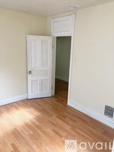 A room with a white door and wooden flooring.