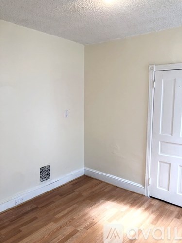 A room with a white door and a light switch on the wall.