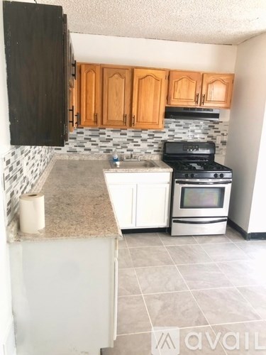 A kitchen with a black fridge, white cabinets, and a black stove top oven.