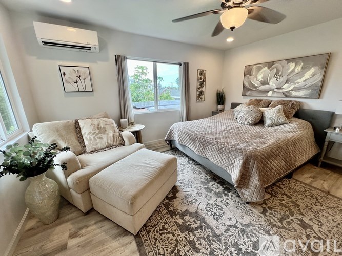 A bedroom with a large bed, a chair, and a potted plant.