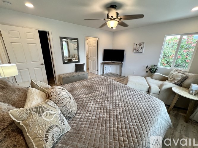 A bedroom with a large bed and a ceiling fan.