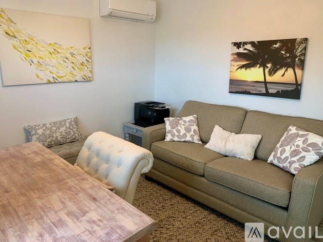 A living room with a couch, chair, and a painting on the wall.