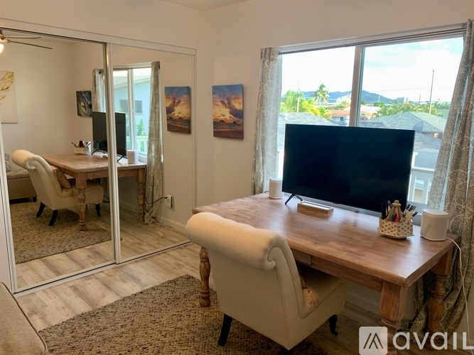 A room with a desk, chair, and a mirrored wall.