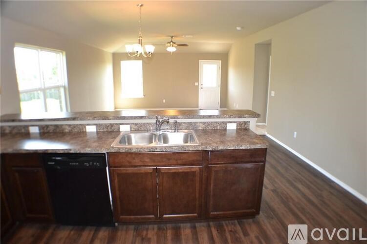 A kitchen with a black dishwasher and wooden cabinets.