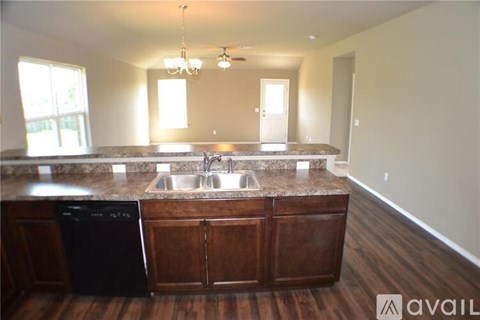A kitchen with a black dishwasher and wooden cabinets.