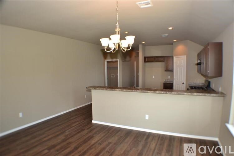 A spacious room with a wooden floor and a chandelier hanging from the ceiling.