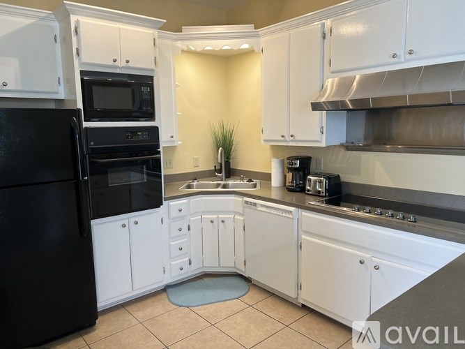 A kitchen with black appliances and white cabinets.