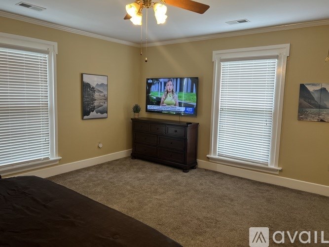 A bedroom with a bed, dresser, and a television playing a show.