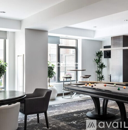 A pool table is in the middle of a room with a chair and a plant.