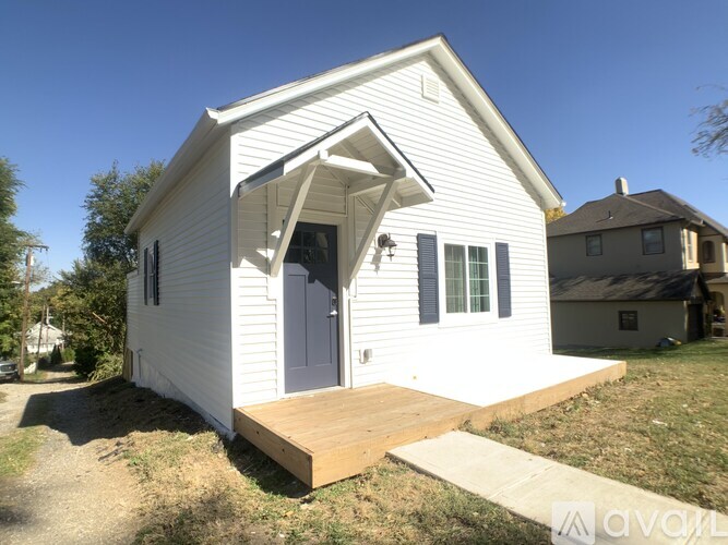 A small white house with a grey door and a wooden porch.