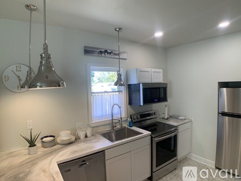 A kitchen with a stainless steel refrigerator and a clock hanging from the ceiling.