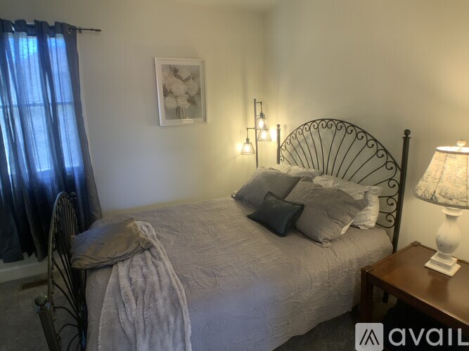 A bedroom with a bed, a chair, and a lamp.