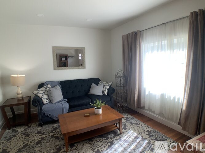 A living room with a blue couch, a wooden coffee table, and a grey rug.