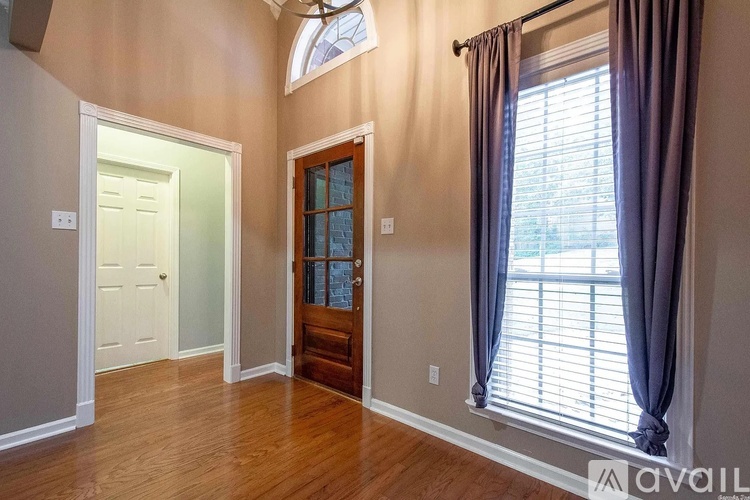A room with a wooden door and a window with curtains.