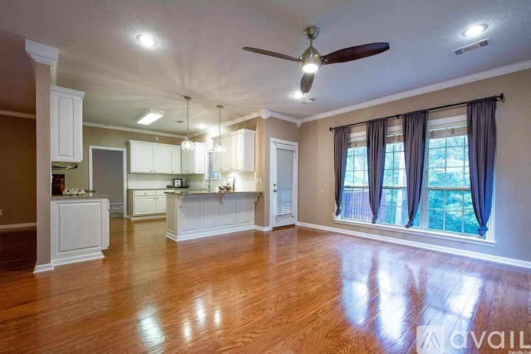 A spacious living room with a ceiling fan and hardwood floors.