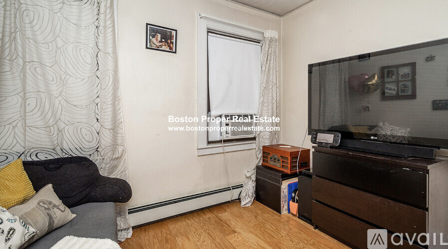 A living room with a couch, a television, and a window.
