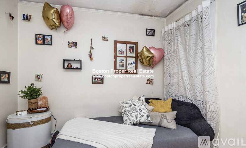 A bedroom with a bed, a nightstand, and a wall decorated with pictures and balloons.