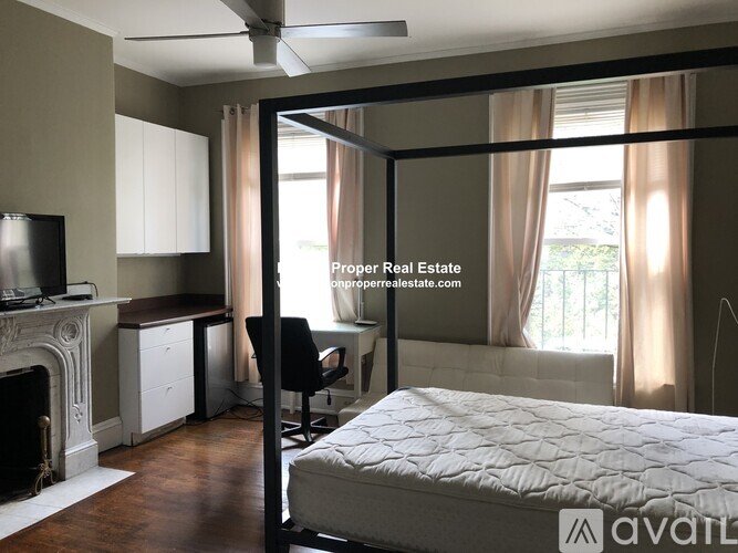 A bedroom with a large bed, a fireplace, and a desk with a chair.