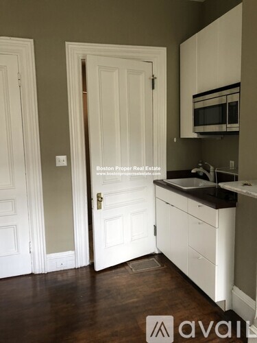 A kitchen with white cabinets and a white door.