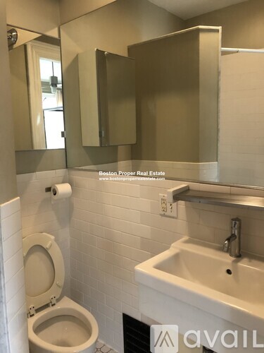 A bathroom with a toilet, sink and mirror.