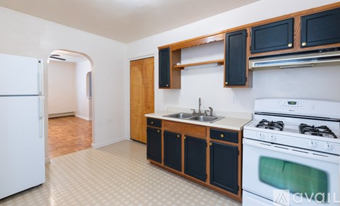 A kitchen with a white fridge, black cabinets, and a white stove top oven.