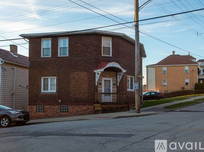A brick house with a porch and a car parked in front.
