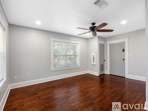 A room with a ceiling fan and wooden flooring.