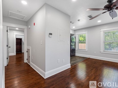 A spacious room with wood flooring and a ceiling fan.