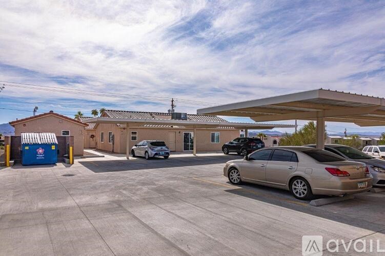 A parking lot with a car parked in front of a building with a sign that reads "avail".