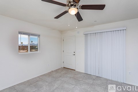 A room with a ceiling fan and a window with a view of a cityscape.