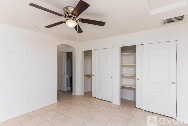 A room with a ceiling fan and white walls.