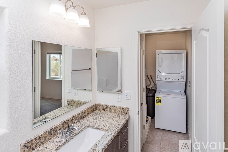A bathroom with a sink, mirror, and a washer and dryer in the doorway.