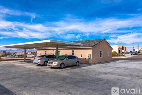 A parking lot with a building and two cars parked in front.