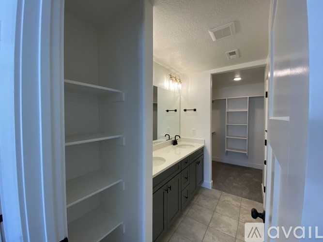 A white refrigerator with empty shelves is in a kitchen with a sink and a mirror.
