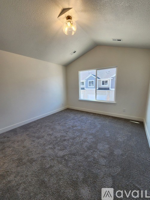 A room with a carpeted floor and a window showing a view of a house.