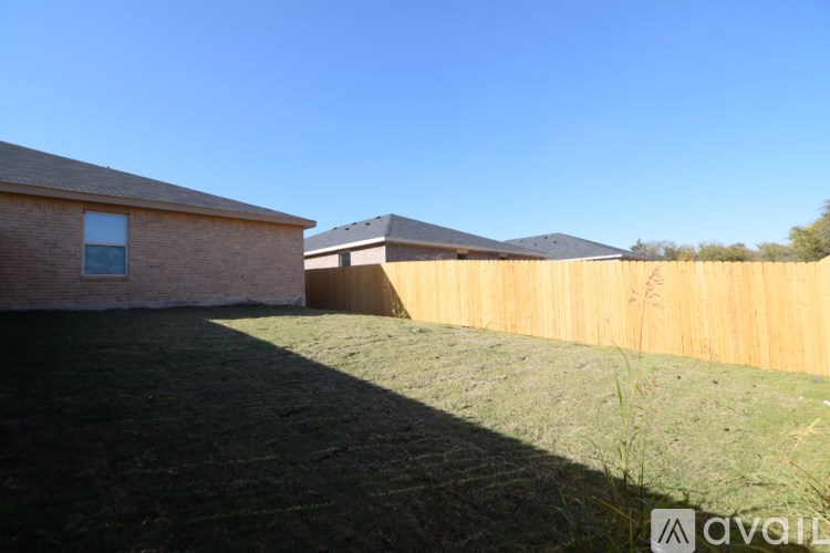 A backyard with a wooden fence and a house.