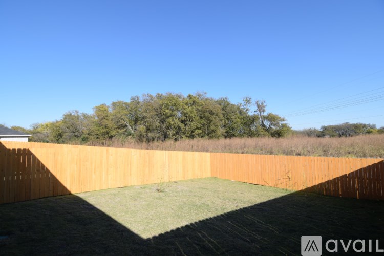 A backyard with a wooden fence and a green lawn.