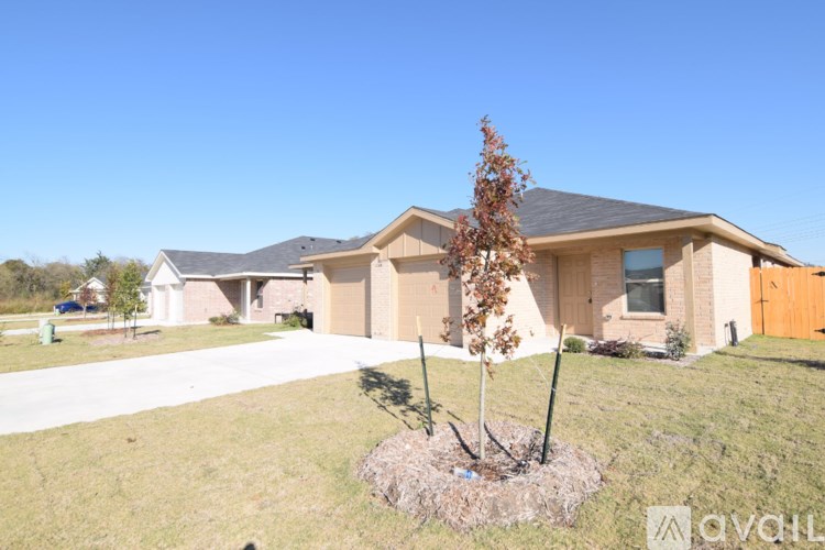A house with a brown roof and a brown garage door is surrounded by a grassy lawn.